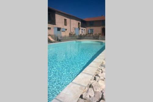 a swimming pool in front of a house at Gîte à la ferme avec piscine in Bernadets-Debat