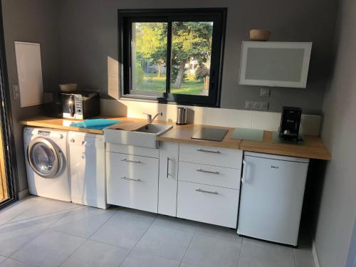 une cuisine avec un évier et une machine à laver dans l'établissement Cabane du Circuit, au Mans