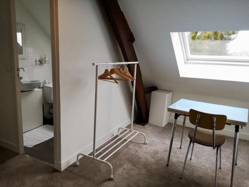 Cette chambre comprend une table, une chaise et un lavabo. dans l'établissement Gite Vénérand, à Acquigny