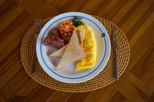 een bord met ontbijtproducten, waaronder een eiersandwich en spek bij Rijet Villa Beach & Restaurant in Nusa Penida