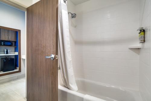 a bathroom with a shower and a white tub at Holiday Inn Express & Suites - Denton South by IHG in Denton