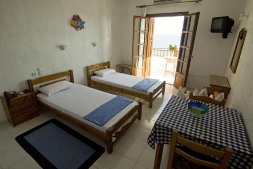 a bedroom with two beds and a table and a window at Hotel Selenunda in Loutraki