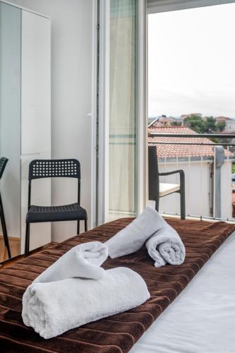 two towels on a bed in front of a window at Rooms&Apartments Zelux in Split