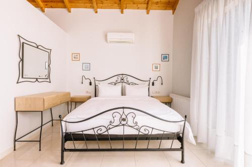 a white bedroom with a bed and a mirror at Anassia Villas in Nafplio