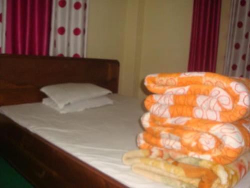 a bed with orange and white blankets on it at Vamose Dawa Lucky's in Sombāri