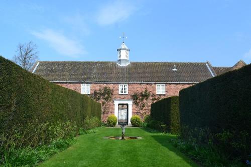 a large brick building with a yard with hedges at Middlethorpe Hall & Spa in York