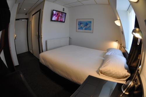 a small room with a bed and a tv at Budget Hotel Le Beau Rivage in Middelburg