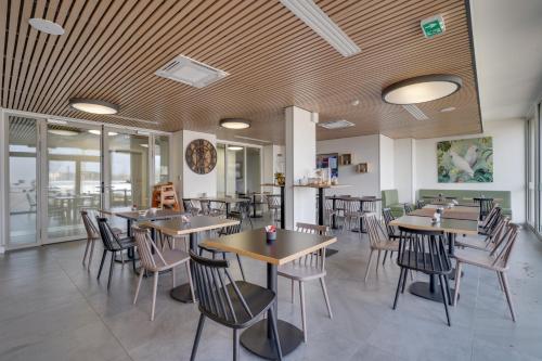 une salle à manger avec des tables et des chaises en bois dans l'établissement All Suites Appart Hôtel - Palaiseau - Massy TGV, à Palaiseau