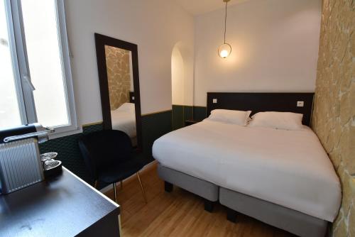 a bedroom with a bed and a desk and a mirror at Hôtel Bonne Nouvelle in Paris