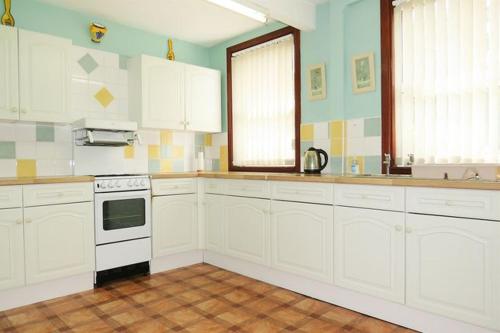 a kitchen with white cabinets and a stove top oven at Beautiful Home Near Worcester Royal Hospital in Hindlip