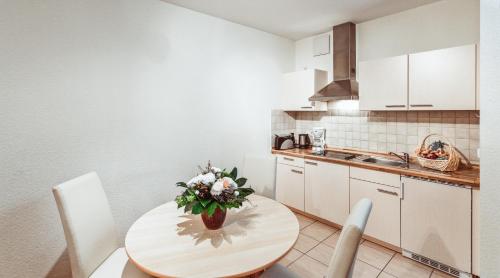 a kitchen with a table with a vase of flowers on it at Aparthotel Münzgasse An der Frauenkirche in Dresden