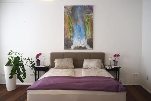 um quarto com uma cama com um quadro na parede em Weghuberhof Ferienwohnungen em Biedermannsdorf