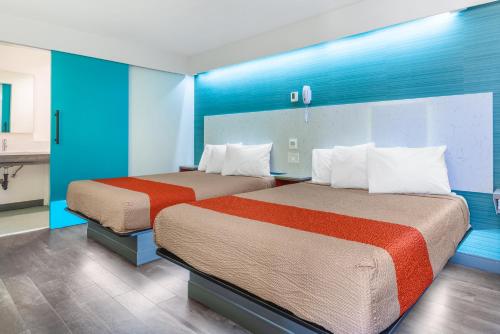 two beds in a hotel room with blue walls at Solo Motel Broadway in Los Angeles