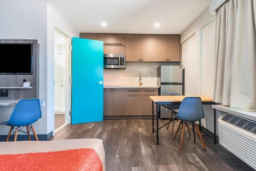 a kitchen with a table and two blue chairs at Solo Motel Broadway in Los Angeles
