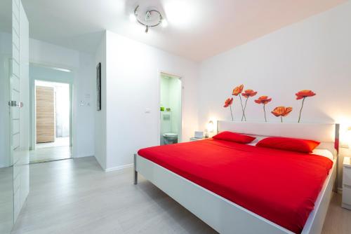 a white bedroom with a red bed with red pillows at Villa Tolja in Dubrovnik