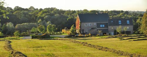 a large house on a hill with a grass field at côté verger B&B in Battice