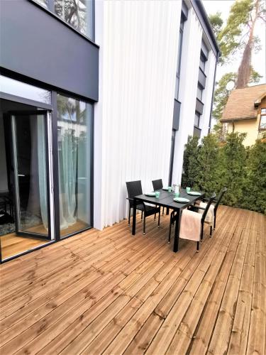 a patio with a table and chairs on a wooden deck at Design apartment LOFT MAJORI with large terrace in Jūrmala
