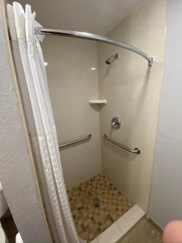 a shower with a shower curtain in a bathroom at Oasis Inn Sacramento- Elk Grove in Sacramento