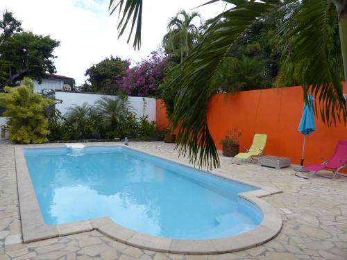 a swimming pool in a yard with an orange wall at Sarithea in Basse-Terre