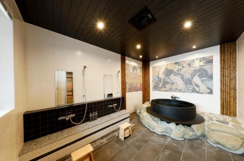a bathroom with a black tub and a sink at 釜之宿 天王寺 in Osaka