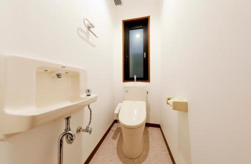 a white bathroom with a toilet and a sink at 釜之宿 天王寺 in Osaka