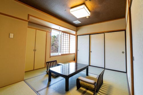 a dining room with a table and chairs and a window at Daitokan in Kusatsu