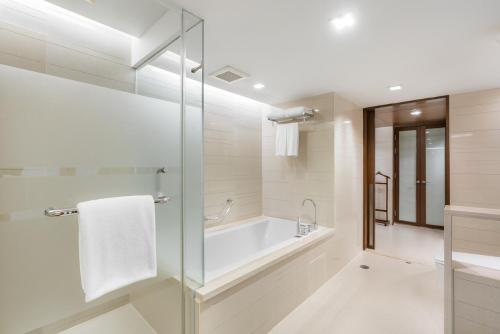 a bathroom with a tub and a glass shower at Pathumwan Princess Hotel - SHA Extra Plus Certified in Bangkok