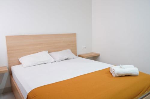 - une chambre avec un lit blanc et une couverture orange dans l'établissement UROOMS Tanah Abang, à Jakarta