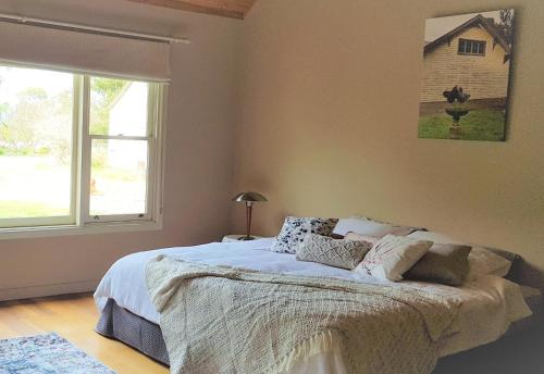 1 dormitorio con 1 cama grande y ventana en Olinda Yarra Cottage, en Yering