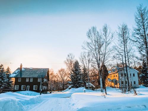 a snow covered yard with a house and buildings at Chalet Banff - 6 bedroom 6 bathroom Ski Lodge in Niseko