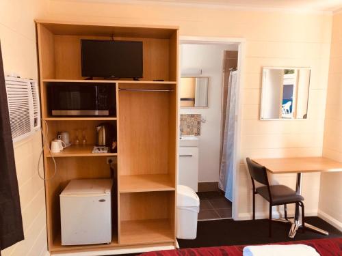 Habitación pequeña con escritorio y mesa con TV. en Red Cedar Motel en Muswellbrook