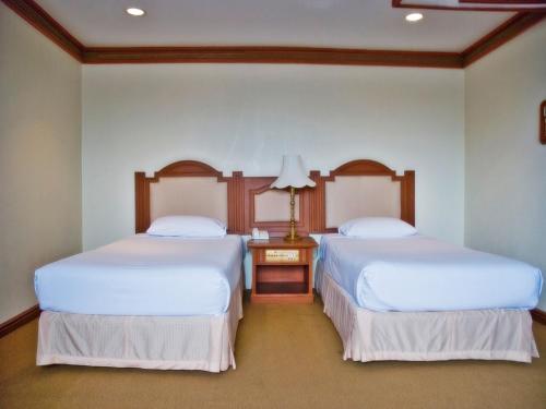 two beds sitting next to each other in a room at Chiang Mai Phucome Hotel in Chiang Mai