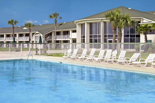 a swimming pool with lounge chairs and a building at Days Inn & Suites by Wyndham Jekyll Island in Jekyll Island