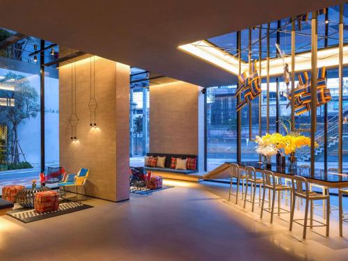 a lobby with a table and chairs in a building at ibis Styles Bangkok Sukhumvit Phra Khanong in Bangkok