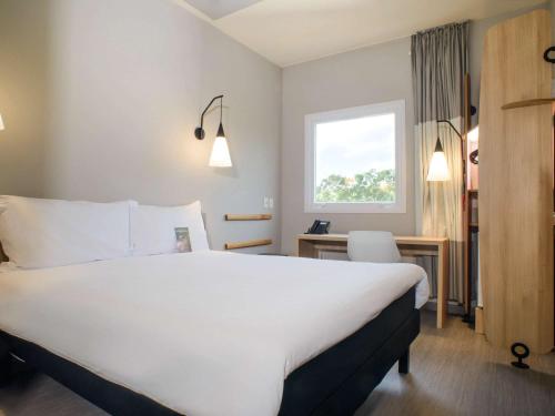 Habitación de hotel con cama blanca grande y escritorio. en ibis Itatiba, en Itatiba