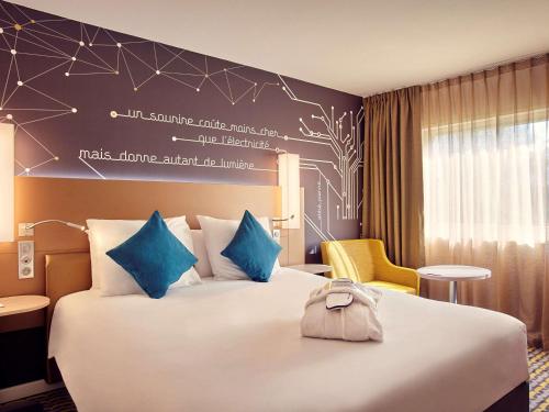 a hotel room with a large bed with a bag on it at Mercure Paris Sud Les Ulis-Courtaboeuf in Les Ulis