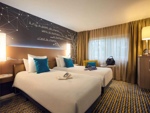 Habitación de hotel con 2 camas y almohadas azules en Mercure Paris Sud Les Ulis-Courtaboeuf, en Les Ulis