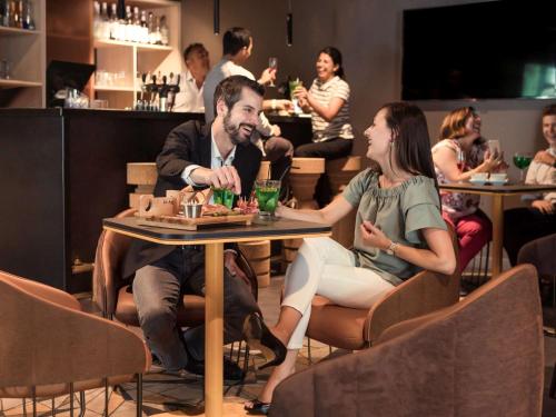 a man and woman sitting at a table in a restaurant at Mercure Paris Sud Les Ulis-Courtaboeuf in Les Ulis