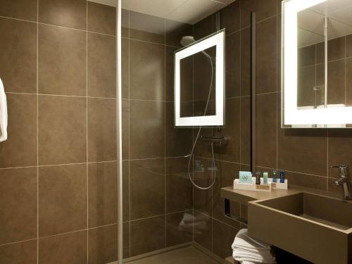 uma casa de banho com um chuveiro, um lavatório e um espelho. em Novotel Fontainebleau Ury em Ury