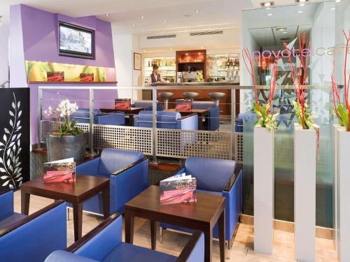 a restaurant with blue chairs and tables at Novotel Amiens Pôle Jules Verne in Boves