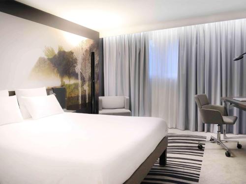 um quarto de hotel com uma cama, uma secretária e cadeiras em Novotel Caen Côte de Nacre em Caen