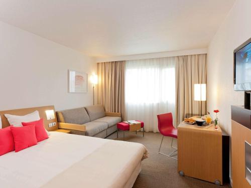 a hotel room with a bed and a couch at Novotel Pau Pyrénées in Lescar