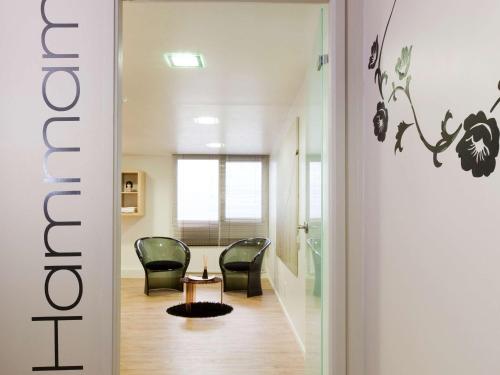 a hallway with two chairs and a table in a room at ibis Styles Lorient Caudan in Caudan