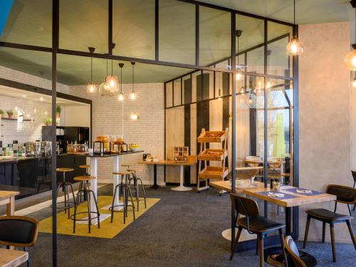 a restaurant with tables and chairs and glass walls at Novotel Le Mans in Le Mans