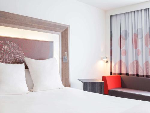 a hotel room with a bed and a red chair at Novotel Coventry in Coventry