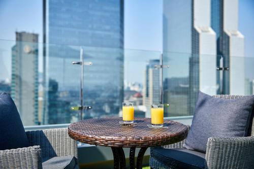 a table with two glasses of orange juice on a balcony at Shilla Stay Samsung COEX Center in Seoul