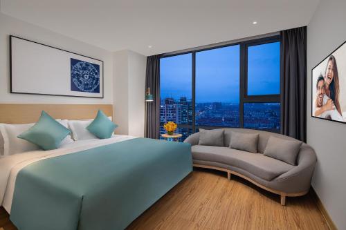 a bedroom with a bed and a couch and a window at Joysuites Nantong in Nantong