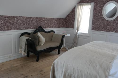 a bedroom with a bed and a chair and a mirror at Petrines Gjestgiveri in Norddal