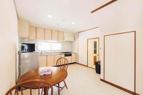 a kitchen with a table and chairs and a refrigerator at stay in 末広 asahikawa in Nagayamachō