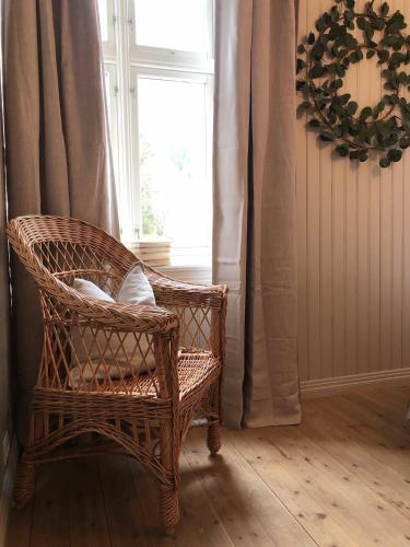 a wicker chair sitting in a room with a window at Petrines Gjestgiveri in Norddal